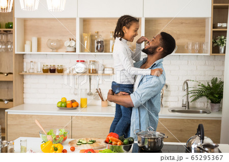 Little girl and cheerful father bonding at kitchen Little girl and cheerful father bonding at kitchen 65295367