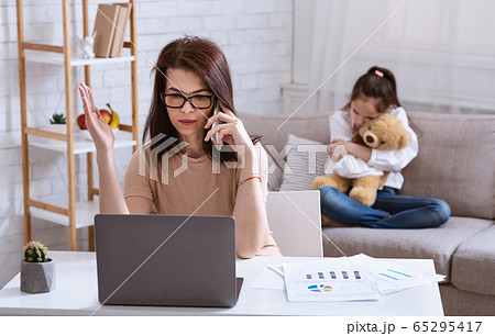 Teen girl feeling lonely and hugging toy while her mom working with gadgets at home Teen girl feeling lonely and hugging toy while her mom working with gadgets at home 65295417