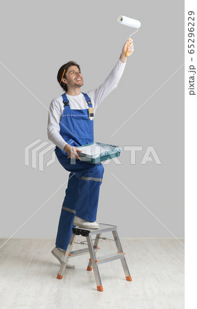 Painting Services Concept. Worker Holding Paint Roller, Applying Dye To Ceiling 65296229