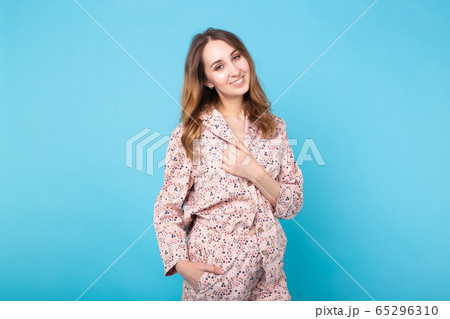Young girl posing in pajamas on blue background. Relax good mood, lifestyle and sleepwear concept. 65296310