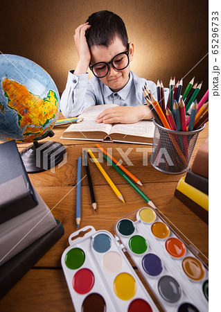 cute little boy schoolboy doing homework at a table with books 65296733