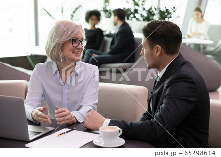 Middle-aged insurer consulting customer during formal meeting in office 65298614