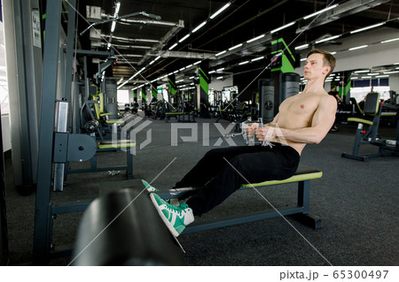 Fitness young man using rowing machine in the gym. Sporty man in the gym 65300497