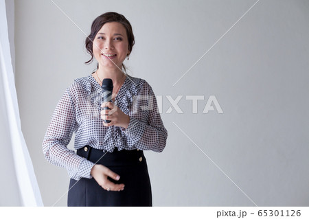 Portrait of a beautiful fashionable Asian woman with a microphone in a business suit at work in the office Portrait of a beautiful fashionable Asian woman with a microphone in a business suit at work in the office 65301126