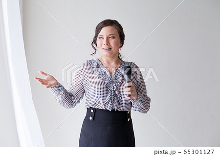 Portrait of a beautiful fashionable Asian woman with a microphone in a business suit at work in the office 65301127