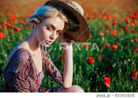 a woman farmer in a field of red poppies 65301656