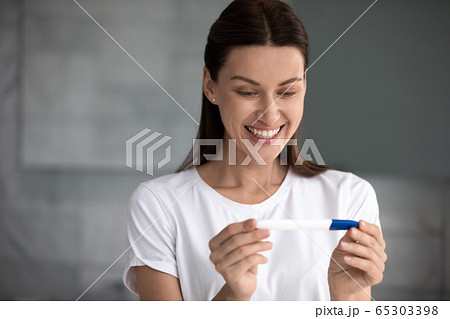 35s woman holding pregnancy test saw two stripes feels happy 65303398