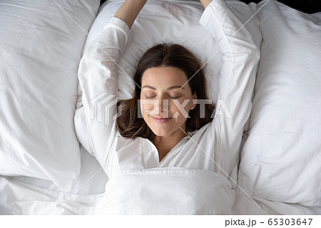 Woman stretching hands waking up after night sleep top view 65303647