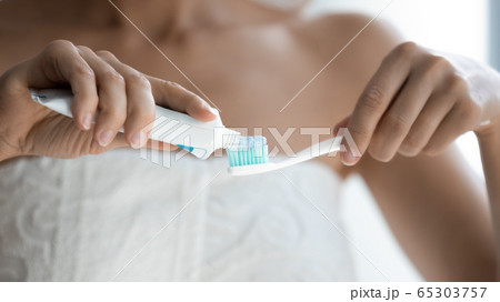 Closeup image toothpaste from tube being applied to toothbrush 65303757