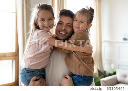 Head shot portrait smiling father holding little daughters in arms Head shot portrait smiling father holding little daughters in arms 65305403