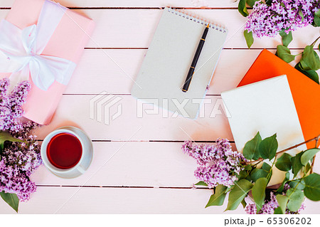 on the white table lilac, gift, notebook, cup of tea 65306202