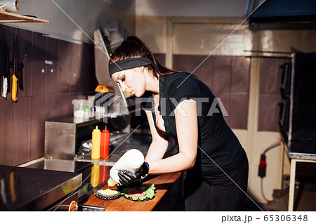 woman chef prepares fresh burgers in the kitchen of the restaurant woman chef prepares fresh burgers in the kitchen of the restaurant 65306348