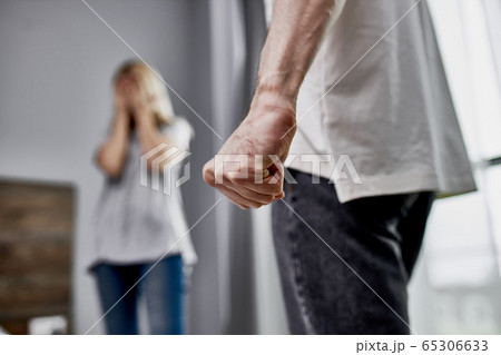 close-up photo of male fist, angry man and scared woman 65306633