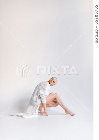 Sensual woman in white cape stretching leg Sensual woman in white cape stretching leg 65306705