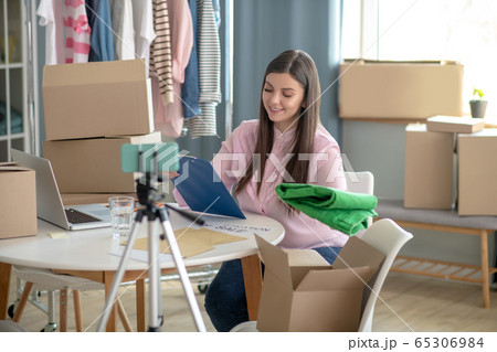 Dark-haired young woman sitting at the table during online sale 65306984