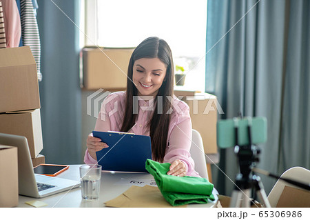 Dark-haired young woman looking at the list and smiling Dark-haired young woman looking at the list and smiling 65306986