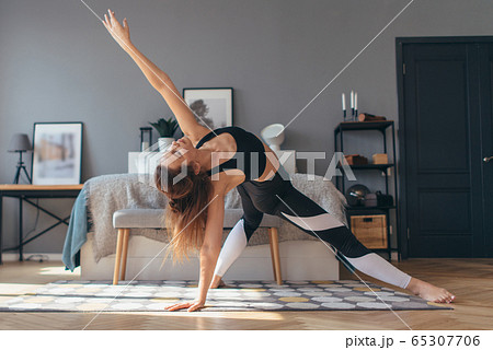 Fit woman trains at home, doing backbend. 65307706