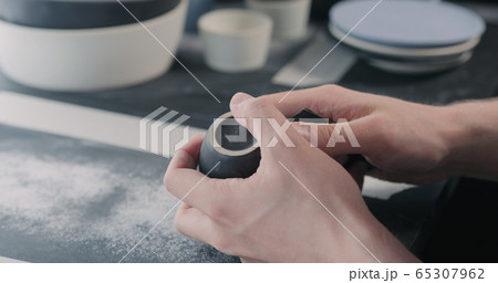 man hands polishing bottom of black ceramic cup 65307962