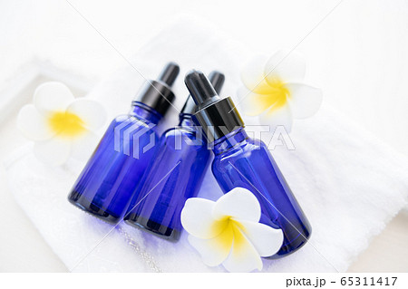 アロマオイルの瓶とプルメリアの花の写真素材