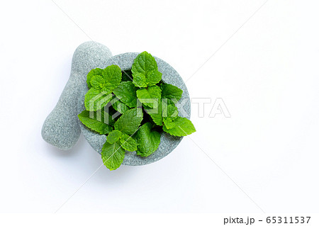 Mint leaves in stone mortar and pestle on white 65311537