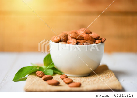 Almonds nuts on bowl with leaf almonds on wooden Almonds nuts on bowl with leaf almonds on wooden 65311818
