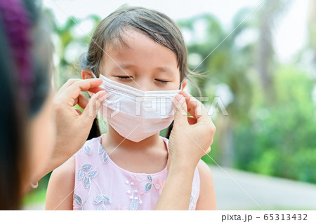 Mother is wearing a cloth mask for little girl protect herself from Coronavirus when child leave the house mom is wearing mask on her nose for safety outdoor activity,illness or Air pollution Mother is wearing a cloth mask for little girl protect herself from Coronavirus when child leave the house mom is wearing mask on her nose for safety outdoor activity,illness or Air pollution 65313432