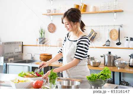 キッチンで料理を作る若い女性 65316147