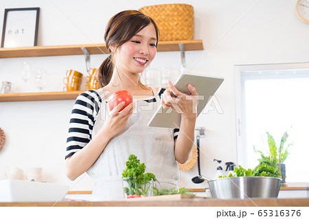 タブレットを見ながら料理を作る若い女性 タブレットを見ながら料理を作る若い女性 65316376