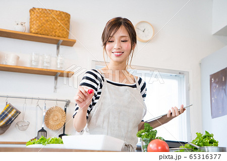 タブレットを見ながら料理を作る若い女性 タブレットを見ながら料理を作る若い女性 65316377