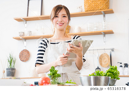 タブレットを見ながら料理を作る若い女性 タブレットを見ながら料理を作る若い女性 65316378