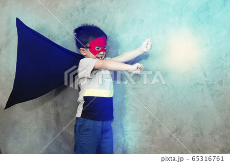 The boy dressed up in a superhero outfit, pretending to fight in studio,has light effect.Boy power concept And development of young children. The boy dressed up in a superhero outfit, pretending to fight in studio,has light effect.Boy power concept And development of young children. 65316761