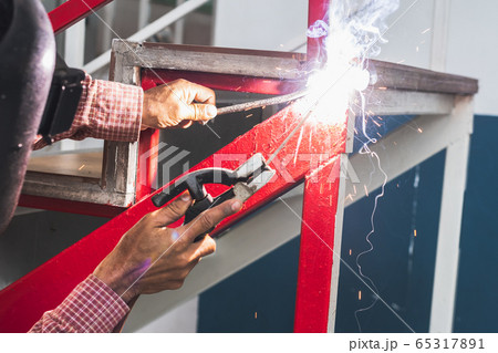 A native working man is welding the metal together A native working man is welding the metal together 65317891
