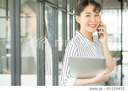 若い　美人　女性　ビジネス　会社員　携帯　電話　スマホ　ノートPC　会話　楽しむ　人物　素材 65320452