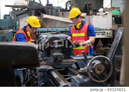 Asian factory engineer wearing yellow hard hat and 65325621