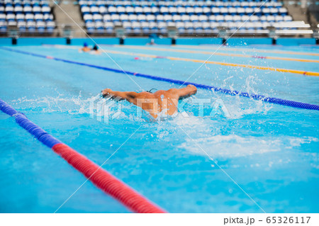 Athletic man swimming in butterfly style in the swimming pool with clear blue water. Athletic man swimming in butterfly style in the swimming pool with clear blue water. 65326117