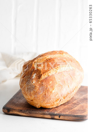 Homemade freshy baked bread on a wooden board and light grey marble table decorated textile towel. Homemade freshy baked bread on a wooden board and light grey marble table decorated textile towel. 65330263