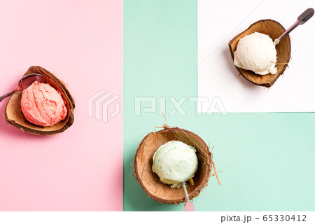 Coconut shells with fresh natural colorful ice-cream on a duotone pastel background with paper sheet Coconut shells with fresh natural colorful ice-cream on a duotone pastel background with paper sheet 65330412