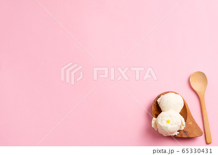 Homemade vanilla ice cream in a natural wooden plate with spoon handmade from olive tree on a pastel pink background. 65330431
