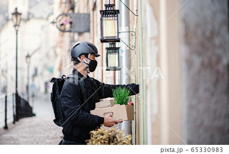 Delivery man courier with face mask delivering groceries in town. Delivery man courier with face mask delivering groceries in town. 65330983