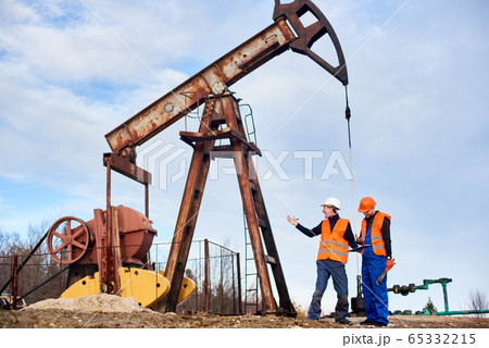 Oil workers in uniforms controlling progress work at local oil pump station on sunny day 65332215