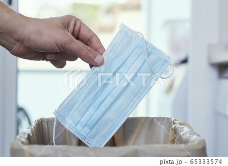 man throwing a surgical mask to the trash can 65333574