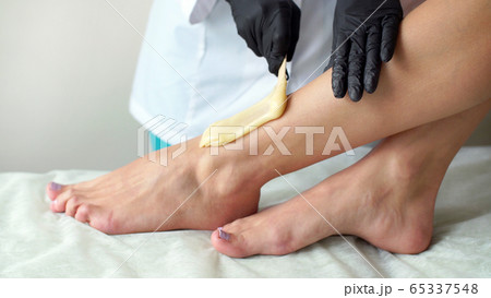 Woman doing foot waxing professional close-up job Woman doing foot waxing professional close-up job 65337548
