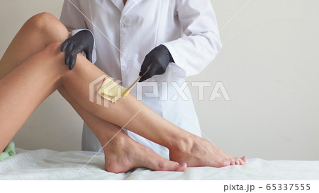 Woman doing foot waxing professional close-up job Woman doing foot waxing professional close-up job 65337555