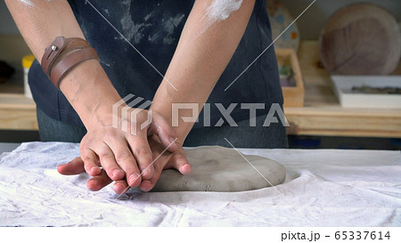 Female sculptor's hands are kneading clay for a ceramic plate Female sculptor's hands are kneading clay for a ceramic plate 65337614