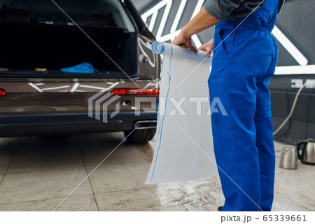 Male worker holds roll of car protection film Male worker holds roll of car protection film 65339661
