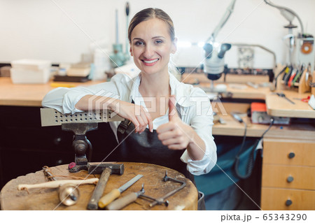 Portrait of a goldsmith in her workshop standing amidst tools 65343290