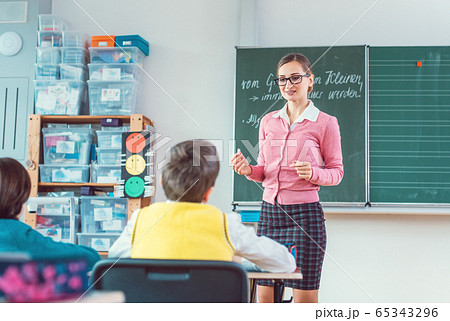 Teacher in class with fourth grade students in front of black board 65343296