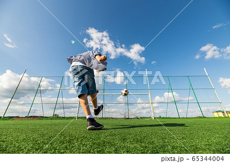 Boy kicking a penalty at goal playing with his father on a green grass. 65344004