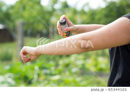 Young woman spraying mosquito, insect repellent in the forrest, insect protection, helathcare concept 65344103