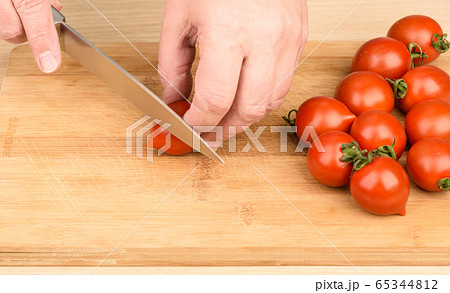 Slicing cherry tomatoes on a cutting board. 65344812